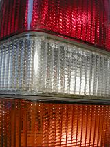 Close up detail of a colorful car rear tail light lens with bands of red, white and orange for driving , indicating or braking