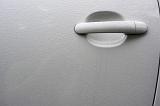 White handle on a car door with beads of moisture from rain or dew and copy space