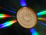 Radiating rays of colorful vivid spectral light on a CD around the central symbol in a concept of communication and data storage