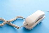 White plastic landline corded telephone with a handset on a blue background with copy space in a communications concept