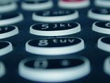 Extreme low angle view of an alphanumeric telephone keypad with black buttons with selective focus to the 5