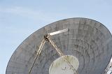 Close up of a parabolic satellite antenna or ground station dish against a blue sky in a telecommunications concept