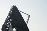 Silhouette of a parabolic dish satellite antenna in side view over a grey sky with copy space in a communications concept