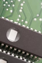 EPROM memory chips with round windows on black backs, installed on green electronic printed circuit board, close-up cropped image with copy space